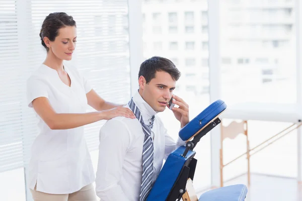 Empresario teniendo masaje de espalda mientras habla por teléfono —  Fotos de Stock