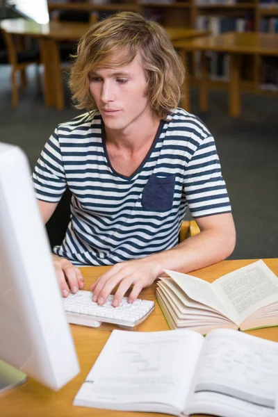 Student studeert in de bibliotheek met computer — Stockfoto