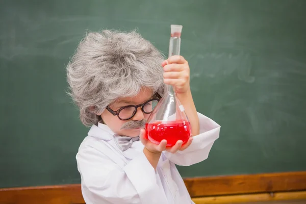 Dressed up pupil looking at red liquid — Stock Photo, Image