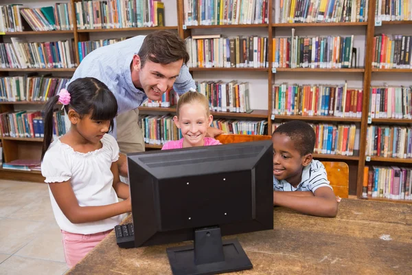 Enseignant et élèves utilisant un ordinateur à la bibliothèque — Photo