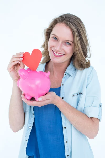 Mulher segurando banco porquinho e coração — Fotografia de Stock