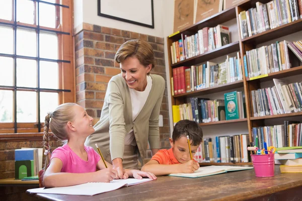 Nauczyciel pomaga uczniom w bibliotece — Zdjęcie stockowe