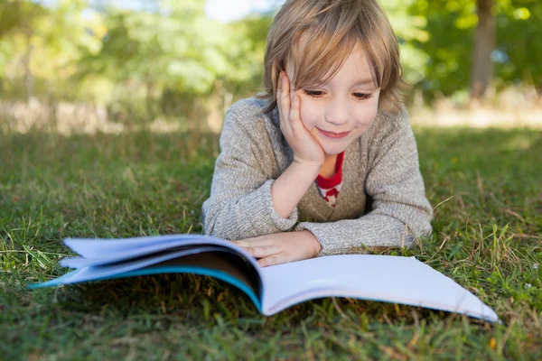 Cute little boy reading in park — Stock Photo, Image