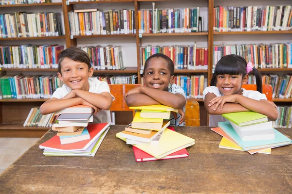 Mignonnes élèves souriant à la caméra à la bibliothèque — Photo
