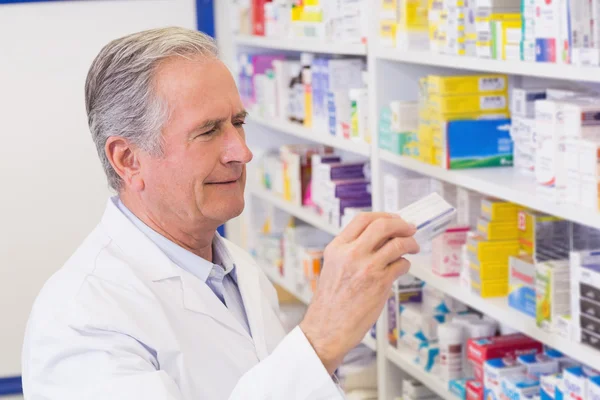 Farmacéutico senior tomando medicamentos de la estantería —  Fotos de Stock