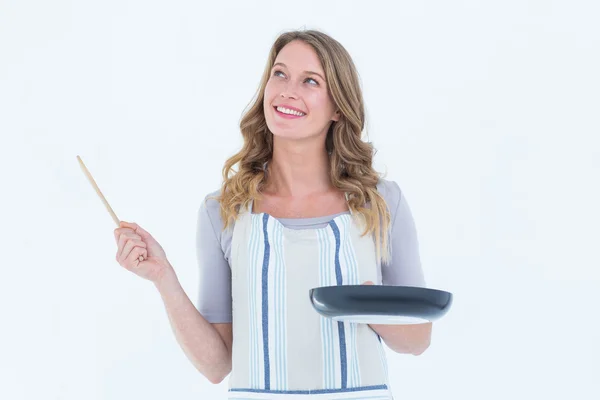 Smiling woman holding frying pan and wooden spoon — Stock Photo, Image