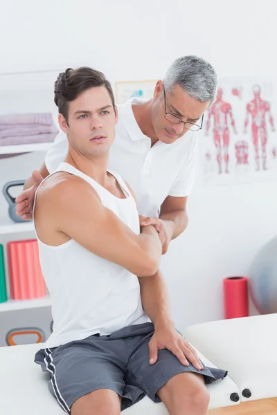 Doctor stretching a young man arm — Stock Photo, Image