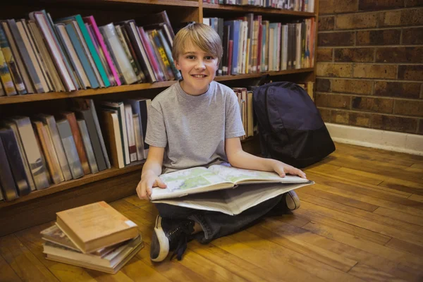 Мальчик читает на полу библиотеки — стоковое фото