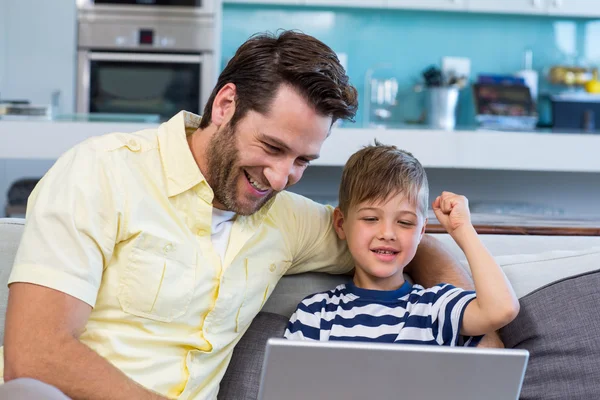 Father and son using laptop on the couch — Stock Photo, Image