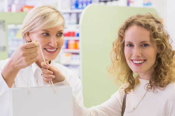 Pharmacist and costumer holding paper bag — Stock Photo, Image