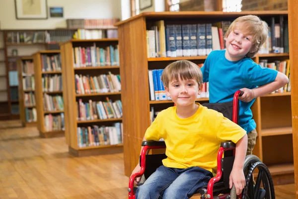 Pupilas lindas sonriendo a la cámara en la biblioteca —  Fotos de Stock