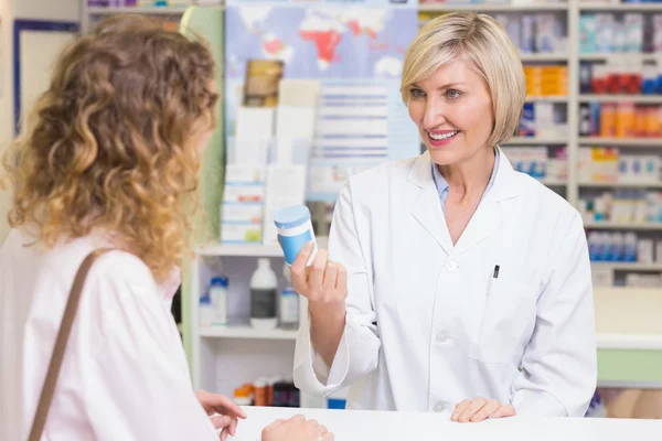 Farmaceut, ukazující lékařství sklenice k zákazníkovi — Stock fotografie