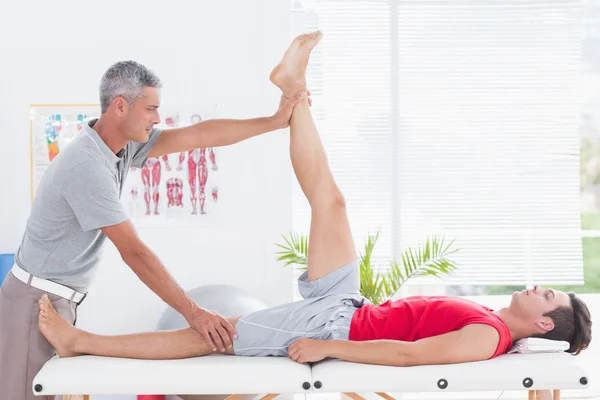 Fysiotherapeut doen been uitrekkende aan zijn patiënt — Stockfoto