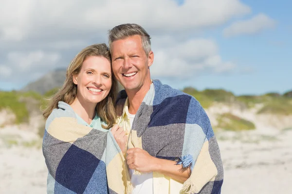 Happy couple wrapped up in blanket — Stock Photo, Image