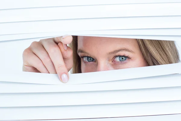 Woman peering through roller blind — Stock Photo, Image