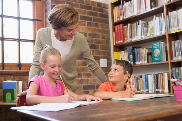 Teacher helping pupils in library — Stock Photo, Image