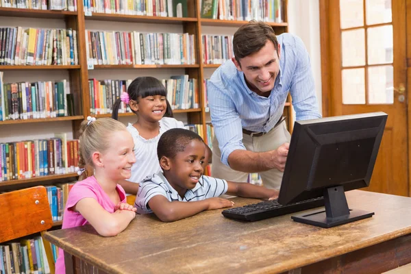 Profesores y alumnos usando ordenador en la biblioteca —  Fotos de Stock