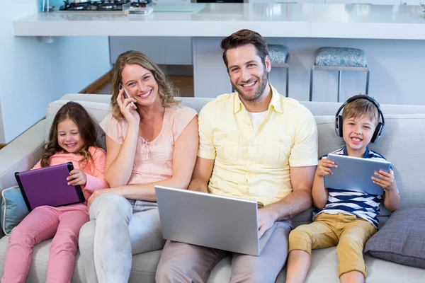 Familia feliz en el sofá juntos usando dispositivos —  Fotos de Stock