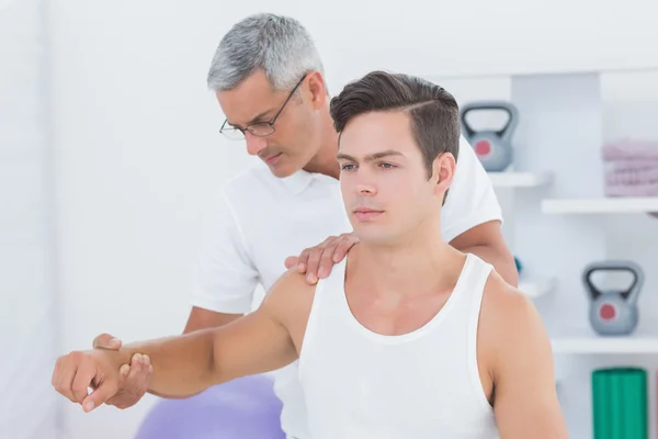 Doctor estirando un brazo de hombre joven — Foto de Stock