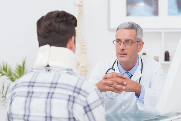 Врач разговаривает с пациентом в шейном корсете — стоковое фото
