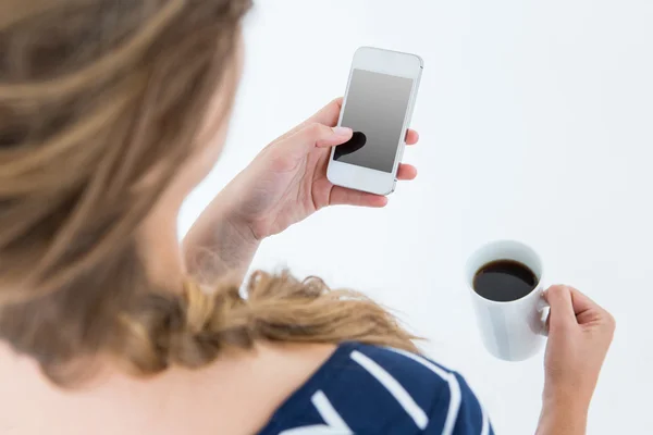 Mujer usando smartphone y sosteniendo taza —  Fotos de Stock