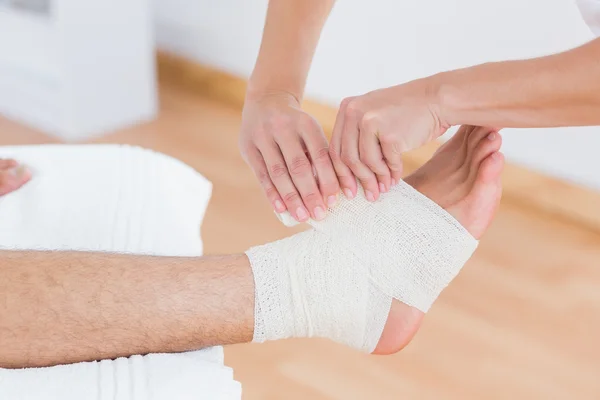 Médico vendando su tobillo paciente — Foto de Stock