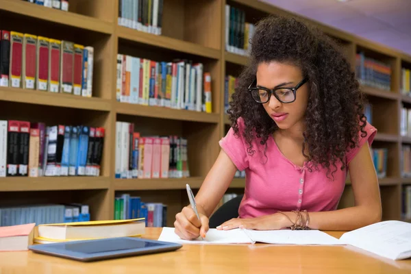 Studente seduto in biblioteca e scrittura — Foto Stock