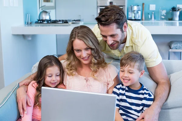 Gelukkige familie op de Bank samen met behulp van laptop — Stockfoto