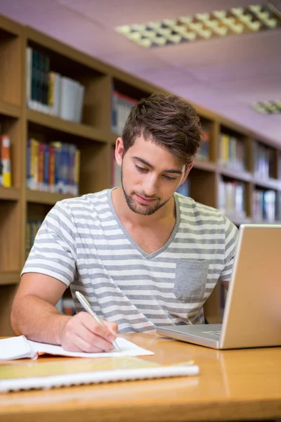 Dizüstü bilgisayar ile kütüphanede okuyan öğrenci — Stok fotoğraf