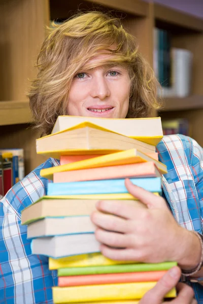 Studente sorridente alla macchina fotografica in biblioteca — Foto Stock