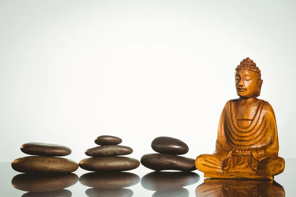 Wooden buddha statue with balancing pebbles — Stock Photo, Image