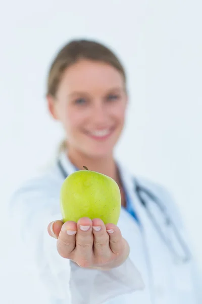 Médecin souriant offrant une pomme — Photo