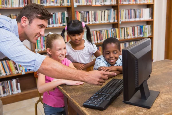 Insegnante e alunni che utilizzano il computer in biblioteca — Foto Stock