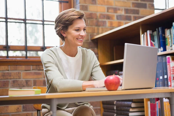 Professora sorrindo usando laptop em uma mesa — Fotografia de Stock
