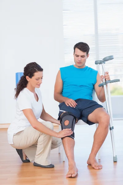 Médico examinando su rodilla paciente —  Fotos de Stock