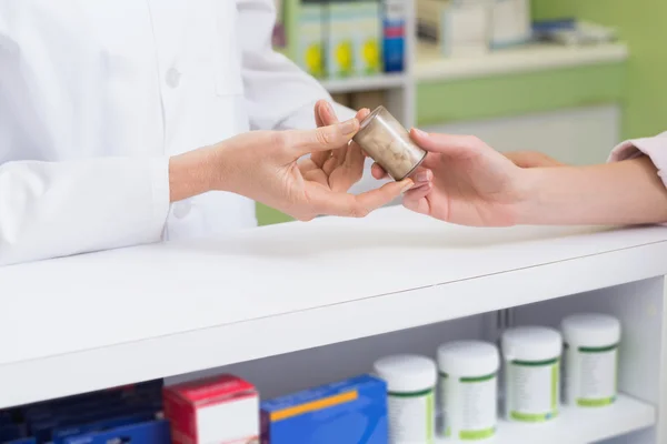 Farmacêutico e cliente segurando frasco de medicina — Fotografia de Stock