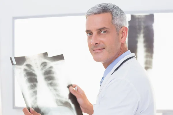 Smiling doctor looking at X-Rays — Stock Photo, Image