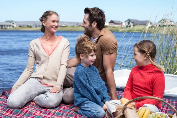 Família feliz fazendo piquenique em um lago — Fotografia de Stock