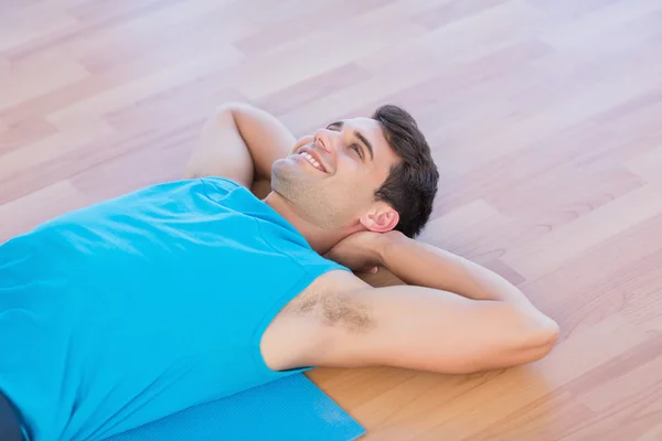 Hombre sonriente acostado en una alfombra de ejercicio — Foto de Stock