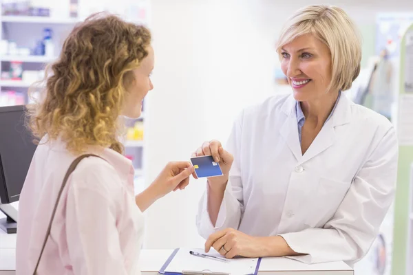 Farmacêutico que dá cartão de crédito ao cliente — Fotografia de Stock
