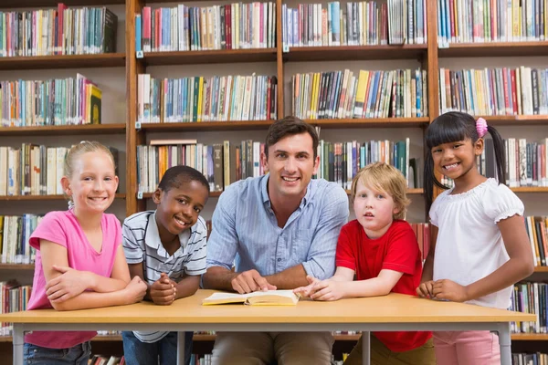 Leraar en leerlingen glimlachen op camera bij bibliotheek — Stockfoto