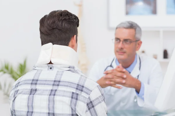 Doctor looking at patient wearing neck brace — Stock Photo, Image