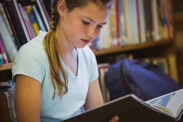 Liten flicka läsning på biblioteket våningen — Stockfoto