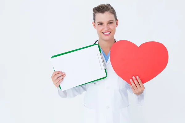 Happy doctor holding clipboard and heart card — Stock Photo, Image