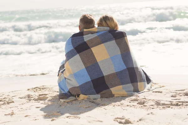 Happy couple wrapped up in blanket — Stock Photo, Image