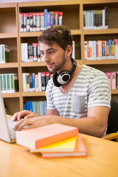 Студент учится в библиотеке с ноутбуком — стоковое фото