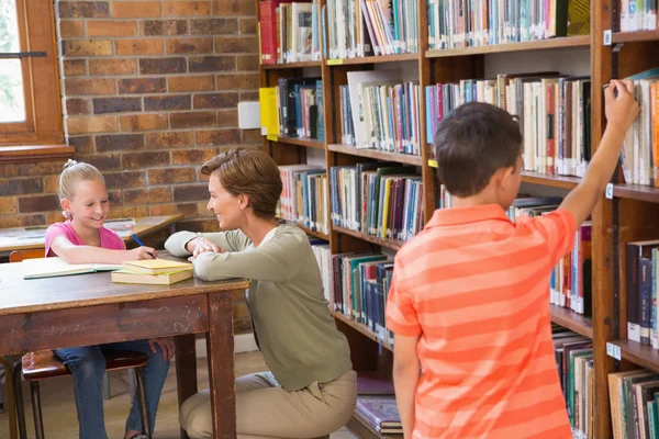 Nauczyciel pomaga uczniów w bibliotece — Zdjęcie stockowe