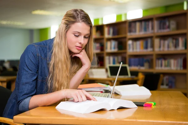 Студент учится в библиотеке с ноутбуком — стоковое фото