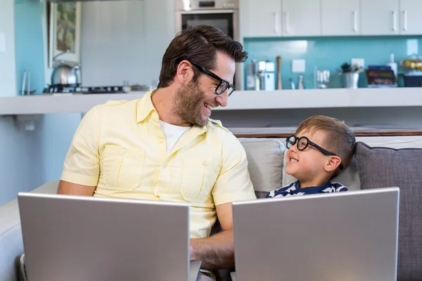 Pai e filho usando laptops no sofá — Fotografia de Stock