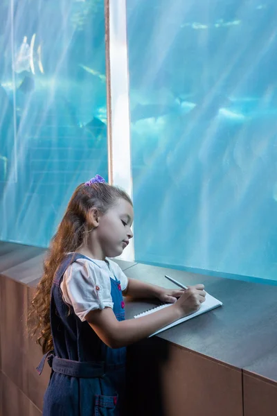 Menina olhando para tanque de peixe — Fotografia de Stock